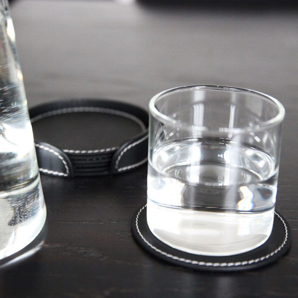 runde-glasbrikker-i-laeder-sort-paa-bord-med-kande-orskov
